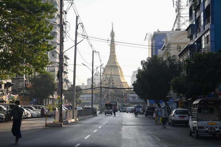 Orang-orang berjalan di sebelah Pagoda Shwedagon di jalan kosong di Yangon, Myanmar.