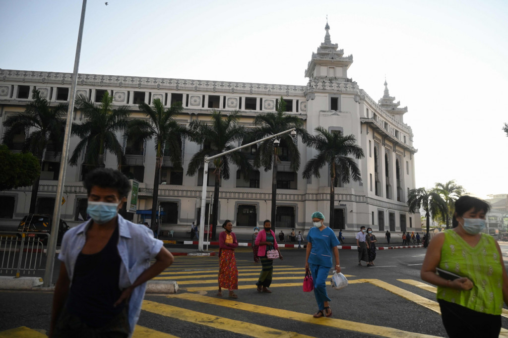 Orang-orang berjalan di sebelah Balai Kota Yangon ketika militer menahan pemimpin de facto Myanmar Aung San Suu Kyi dan presiden Myint dalam kudeta.