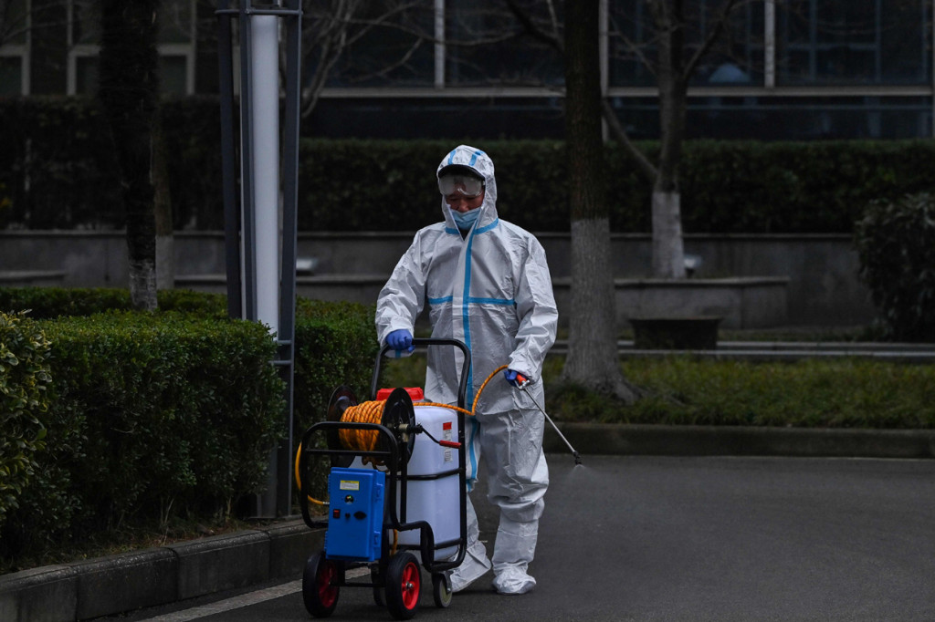 Sementara seorang petugas, yang juga mengenakan APD, medisinfeksi jalan di luar usai mereka masuk.