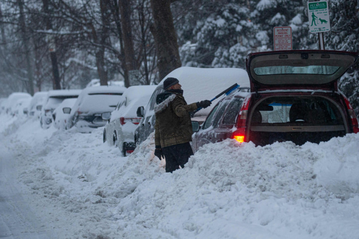 Seorang pria membersihkan mobil saat badai musim dingin di Weehawken, New Jersey. AFP Photo/Kena Betancur 