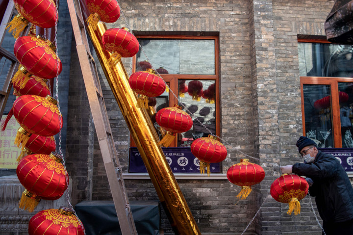 Seorang pekerja memasang lentera tradisionl Tiongkok di sepanjang gang menjelang Tahun Baru Imlek di Beijing, Tionngkok.
