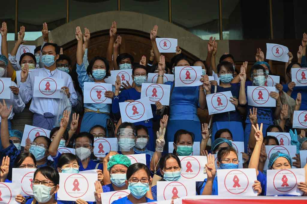 Mahasiswa universitas menunjukkan simbol tiga jari dan pita merah yang menyerukan pembangkangan sipil selama protes melawan kudeta militer, di Universitas Dagon di Yangon pada Jumat, 5 Februari 2021.