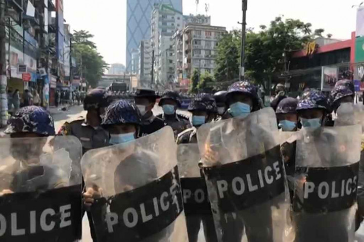 Sementara pasukan kepolisian bersiap dengan tameng mereka untuk memblokade jalan-jalan di dekat aksi demonstrasi tersebut.