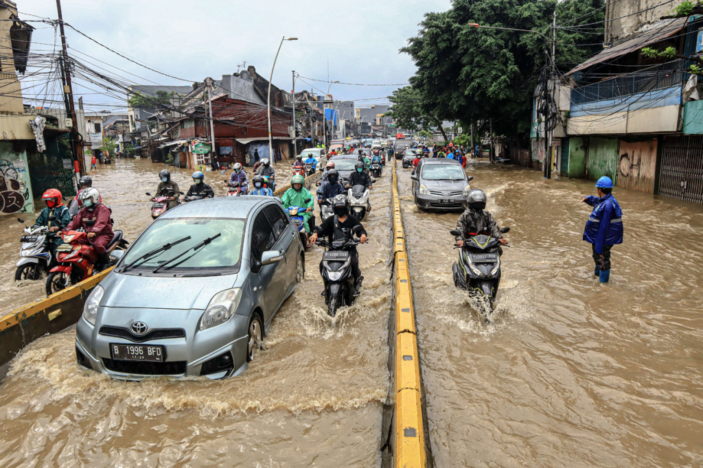 Pengendara di lokasi memanfaatkan jalur bus untuk menghindari genangan air yang merendam jalur lambat.