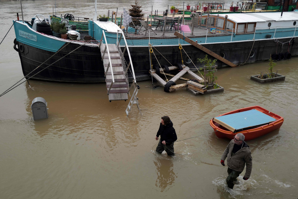 Orang-orang mengevakuasi barang-barang mereka dengan perahu kecil dari tongkang, di tepi sungai Seine yang banjir di Paris. AFP Photo/Valery Hache