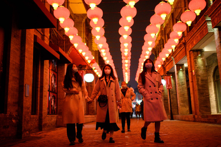 Orang-orang berjalan di bawah lentera Tiongkok tradisional di kawasan Qianmen.