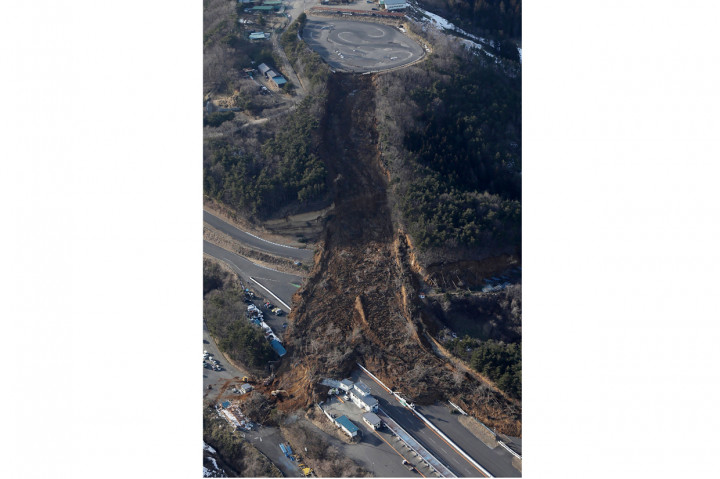Material longsor tampak menutupi jalur sirkuit di kota Nihonmatsu, Fukushima. Sejumlah bangunan di pinggir sirkuit juga tertimbun manterial longsor.