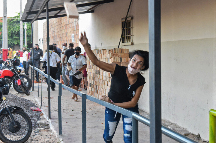 Seorang kerabat narapidana melempar batu bata ke polisi di luar penjara Tacumbu setelah kerusuhan terjadi di dalam penjara.