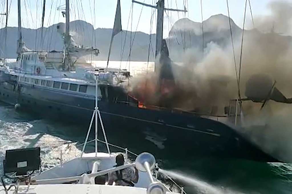 Petugas pemadam kebakaran berjibaku untuk memadamkan api yang melalap sebuah kapal pesiar di lepas pantai pulau liburan Langkawi, Malaysia, Kamis, 18 Februari 2021.