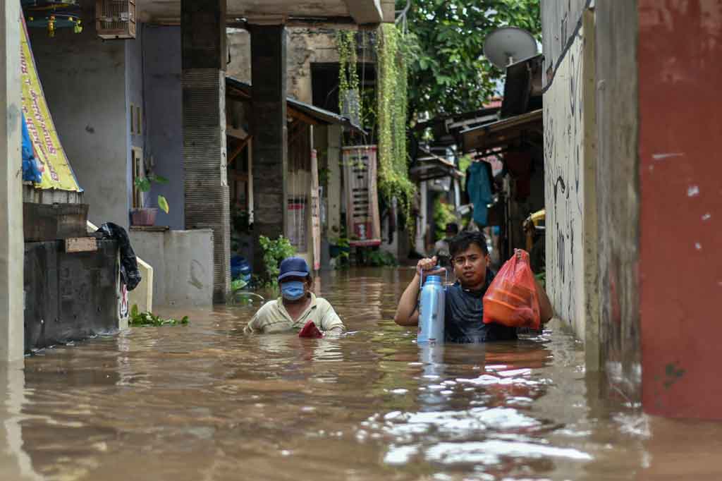Warga melintasi banjir yang merendam kawasan Cipinang Melayu, Jakarta Timur, Jumat, 19 Februari 2021.