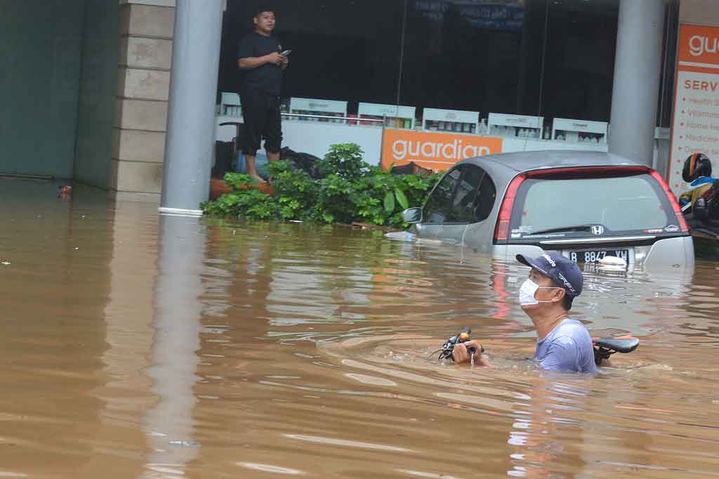 Warga menuntun sepedanya menerobos banjir di Jalan Raya Kemang, Jakarta Selatan.