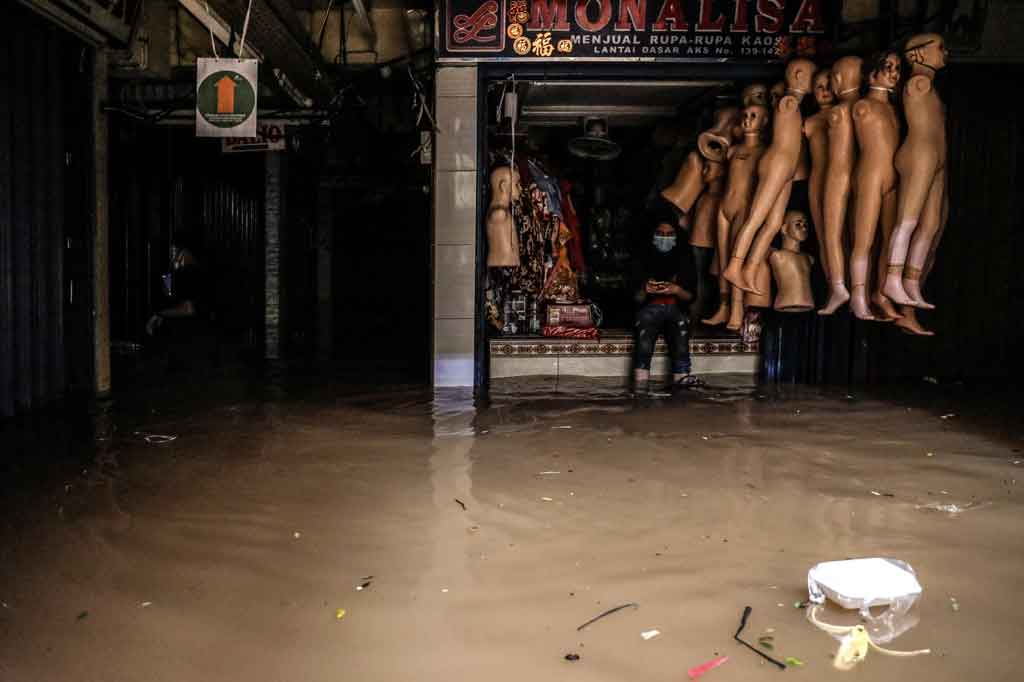 Nampak para pedagang hilir mudik menyelamatkan barang dagangan mereka, sementara beberapa lainnya terlihat berjaga-jaga di area toko yang terendam banjir.