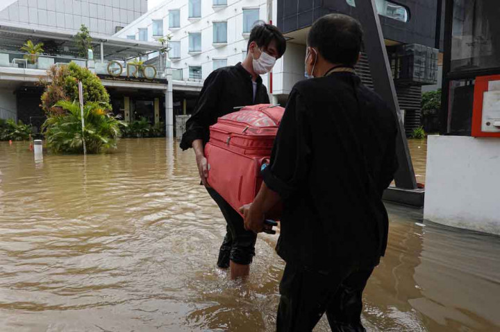 Petugas hotel membawa koper milik tamu saat banjir melanda kawasan Kemang, Jakarta Selatan, Sabtu, 20 Februari 2021.