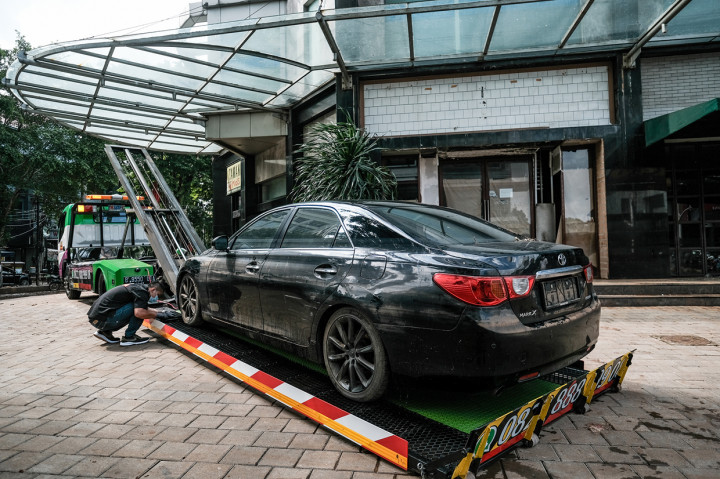 Kini, mobil sudah bisa dievakuasi menggunakan mobil derek. Warga yang berolahraga membantu proses evakuasi.