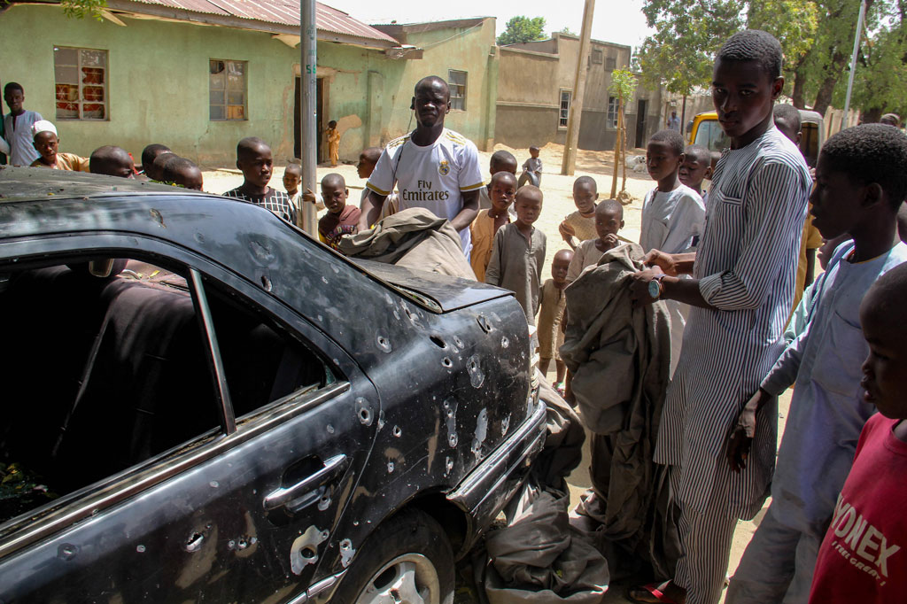 Penduduk mengelilingi bangkai mobil yang terkena serangan oleh anggota jihadis Boko Haram di distrik Adam Kolo, Maiduguri pada Rabu, 24 Februari 2021.