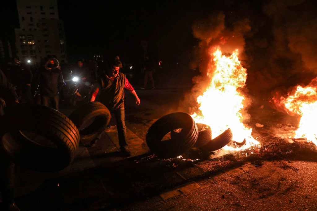 Pengunjuk rasa berdiri di depan ban yang dibakar selama masa protes di Beirut, Lebanon, Selasa (2/3/2021) waktu setempat.