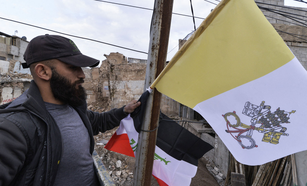 Pekerja mengibarkan bendera Irak dan Takhta Suci Vatikan di tiang-tiang jalan di kota Mosul, Irak, Kamis, 4 Maret 2021.