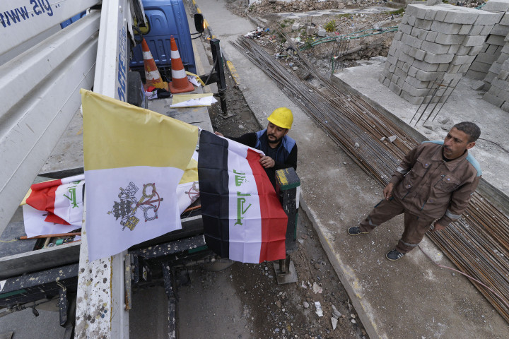 Para pekerja memasang bendera Irak dan Takhta Suci Vatikan di tiang-tiang jalan di kota Mosul, Irak, Kamis, 4 Maret 2021.