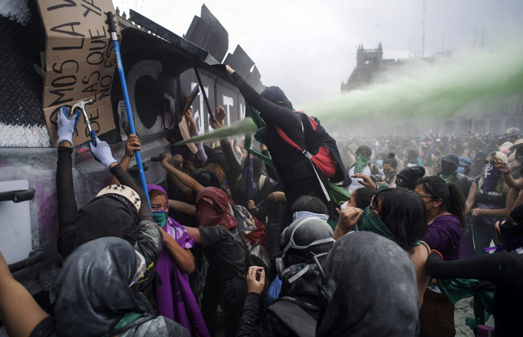 Petugas keamanan menembakkan semprotan merica setelah pengunjuk rasa berusaha merobohkan dinding logam. Pemerintah Mexico City mengklaim