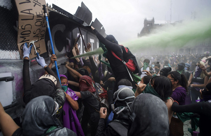 Petugas keamanan menembakkan semprotan merica setelah pengunjuk rasa berusaha merobohkan dinding logam. Pemerintah Mexico City mengklaim