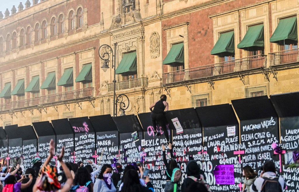 Demonstran memanjat barikade yang melindungi Istana Nasional selama pawai memperingati Hari Perempuan Internasional dan memprotes kekerasan gender di Mexico City, Meksiko.
