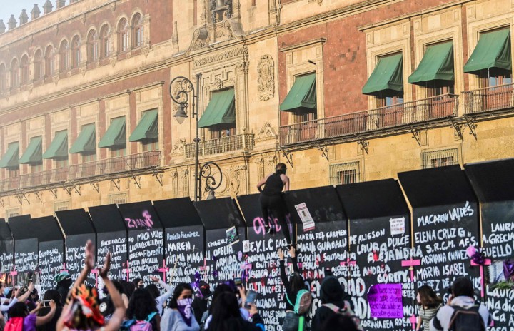Demonstran memanjat barikade yang melindungi Istana Nasional selama pawai memperingati Hari Perempuan Internasional dan memprotes kekerasan gender di Mexico City, Meksiko.