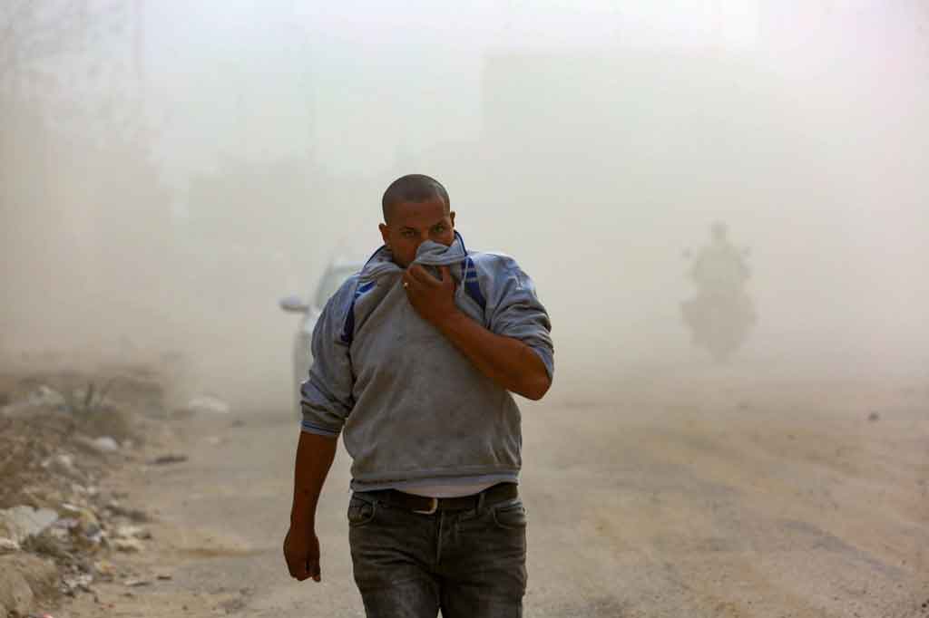 Asap tebal menyelimuti jalanan, memaksa orang yang lewat untuk menutupi wajah mereka dengan pakaian untuk melindungi mereka dari asap.