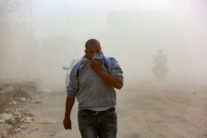 Asap tebal menyelimuti jalanan, memaksa orang yang lewat untuk menutupi wajah mereka dengan pakaian untuk melindungi mereka dari asap.