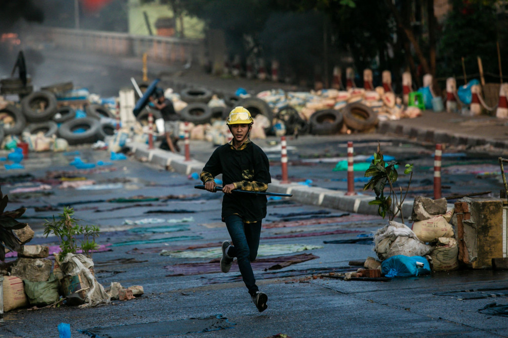 Seorang pengunjuk rasa yang membawa pedang berlari di sepanjang jalan selama demonstrasi menentang kudeta militer di Yangon.