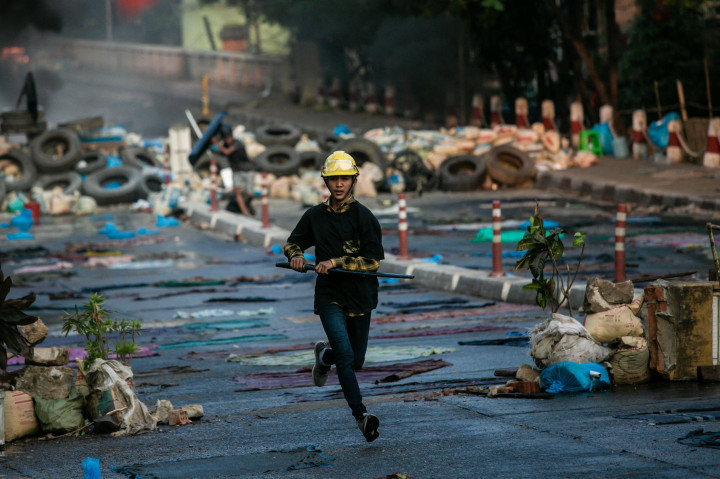 Seorang pengunjuk rasa yang membawa pedang berlari di sepanjang jalan selama demonstrasi menentang kudeta militer di Yangon.