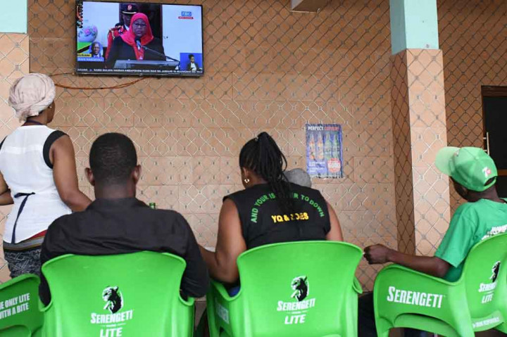 Perempuan berusia 61 tahun itu mengenakan setelan hitam dan kerudung merah, mengambil sumpah jabatan di Dar es Salaam, sebelum memeriksa pasukan di parade militer dan menerima penghormatan meriam.  