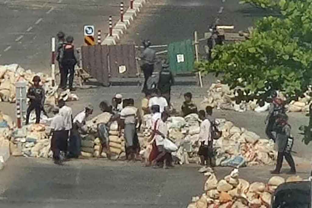 Militer Myanmar memaksa warga sipil untuk membongkar barikade darurat dari bambu, batu bata, dan ban karet yang terbakar di kota terbesar Myanmar, Yangon, Sabtu, 20 Maret 2021. Barikade tersebut tah ubahnya seperti zona perang perkotaan.