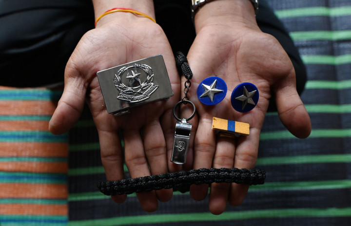 Seorang polisi Myanmar, yang melarikan diri dari Myanmar dan menyeberang secara ilegal ke India, memegang gesper seragam, peluit, dan lencana berdering di tempat penampungan sementara di lokasi yang dirahasiakan di negara bagian Mizoram timur laut India.