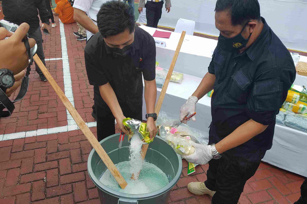 Petugas memusnahkan barang bukti narkoba dengan cara dilarutkan di air.