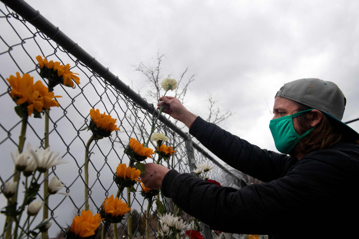 Warga meninggalkan karangan bunga di sepanjang pagar yang dipasang di sekitar tempat parkir tempat penembakan massal yang terjadi di toko King Soopers di Boulder, Colorado.