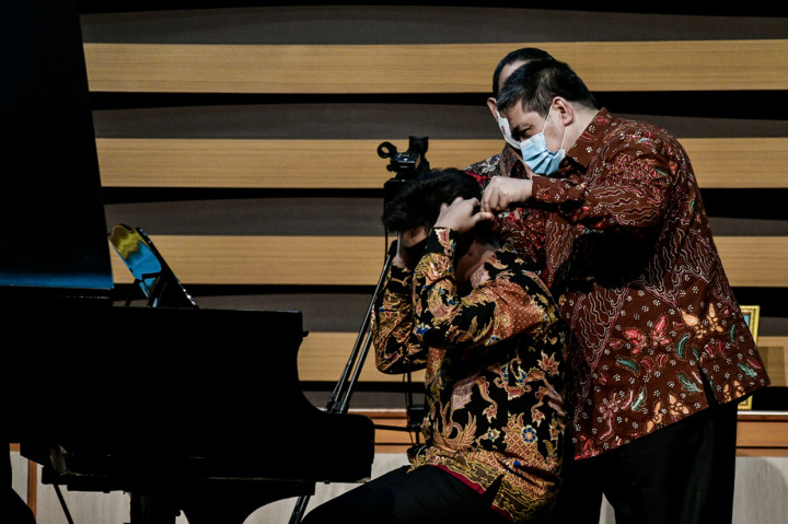 Asisten Deputi Bidang Pembangunan Manusia dan Kebudayaan Kementrian Sekretariat Negara Hanung Cahyono (kanan) menutup mata Jefri Setiawan (kiri) sebelum memainkan pianonya di panggung Audiotorium Universitas Yarsi, Jakarta.