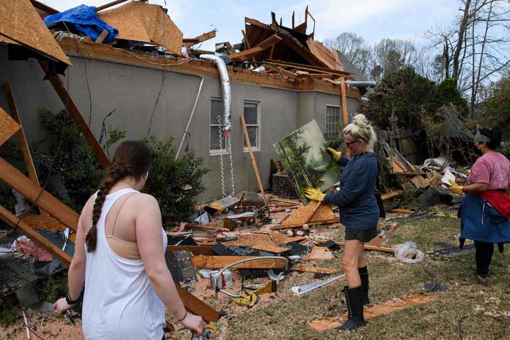 Sukarelawan membantu membersihkan puing-puing di sekitar rumah yang hancur setelah tornado menerjang komunitas Eagle Point selatan Birmingham, Alabama, AS, pada Jumat, 26 Maret 2021.