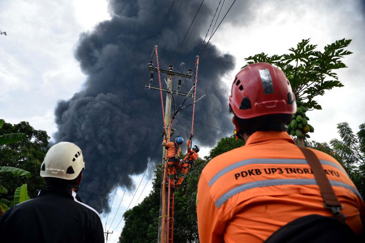 Petugas Perusahaan Listrik Negara (PLN) memperbaiki aliran listrik yang sempat terputus akibat terbakarnya kilang minyak Pertamina di Kawasan Balongan, Indramayu, Jawa Barat. 