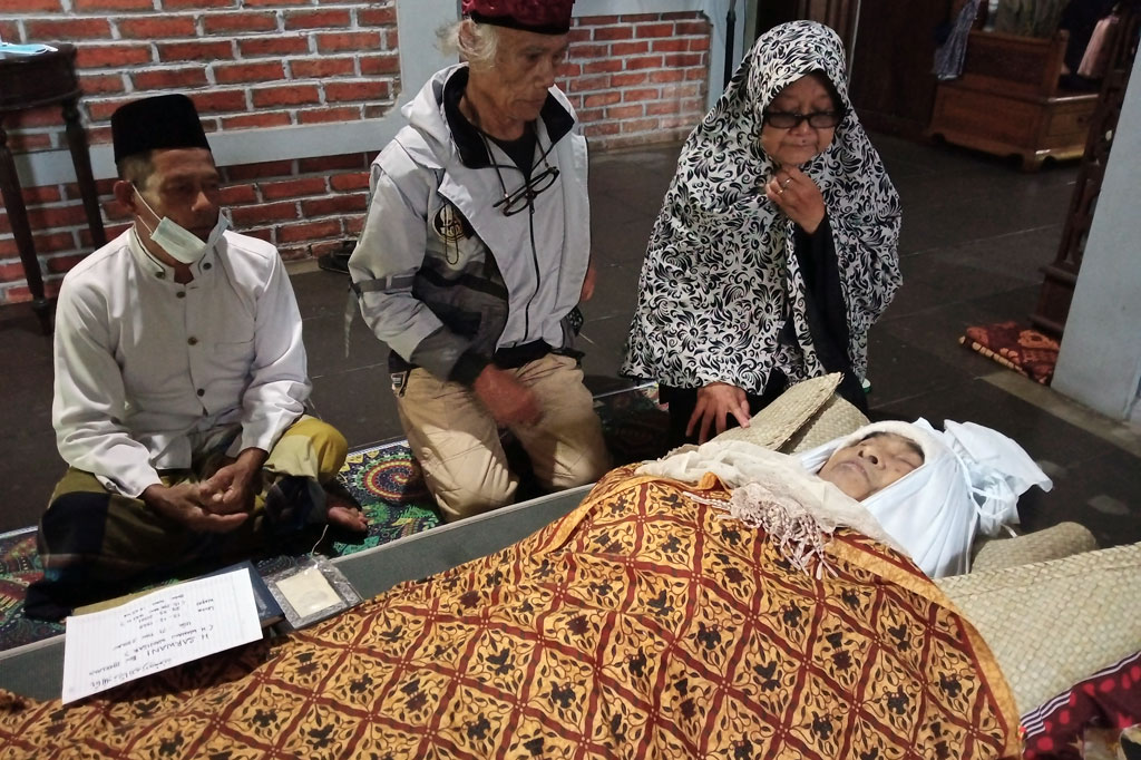 Istri Almarhum H Sarwani atau lebih dikenal sebagai Wawan Wanisar, Tatik dan aktor senior Zainal Abidin atau Diding Boneng berdoa di depan jenazah di rumah duka di Kalisuren, Tajurhalang, Bogor, Jawa Barat, Selasa, 30 Maret 2021.