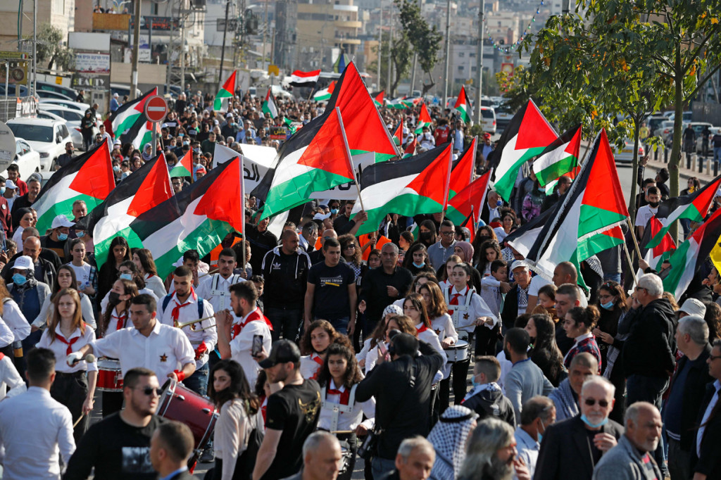 Demonstran mengibarkan bendera Palestina selama unjuk rasa di kota Arraba, Arab-Israel utara, pada 30 Maret 2021, memperingati 'Land Day' atau Hari Tanah. 