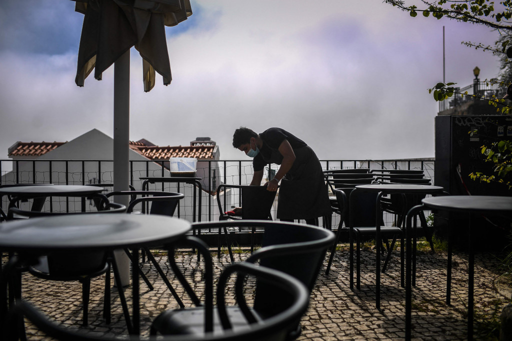 Pramusaji membersihkan kursi di viewpoint Portas do Sol di Lisbon saat pemerintah melonggarkan pembatasan virus korona.