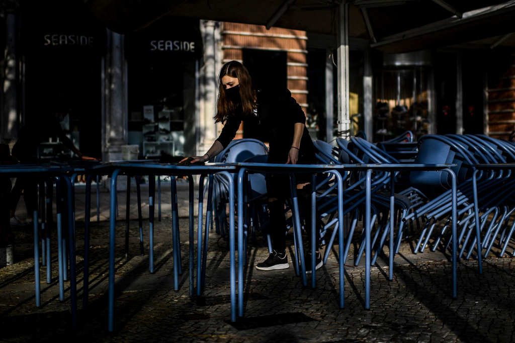 Pramusaji membawa kursi pada pagi hari sebelum pembukaan kembali teras kafe.