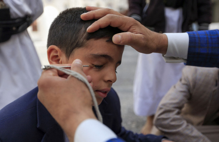 Seorang pria Yaman mengoleskan kosmetik tradisional Kohl ke kelopak mata remaja selama bulan puasa Ramadan di Masjid Sanaa.