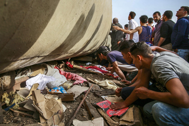 Orang-orang melihat ke bawah gerbong penumpang yang terbalik di lokasi kecelakaan kereta api di kota Toukh di provinsi Qalyubiya Delta Nil tengah Mesir.
