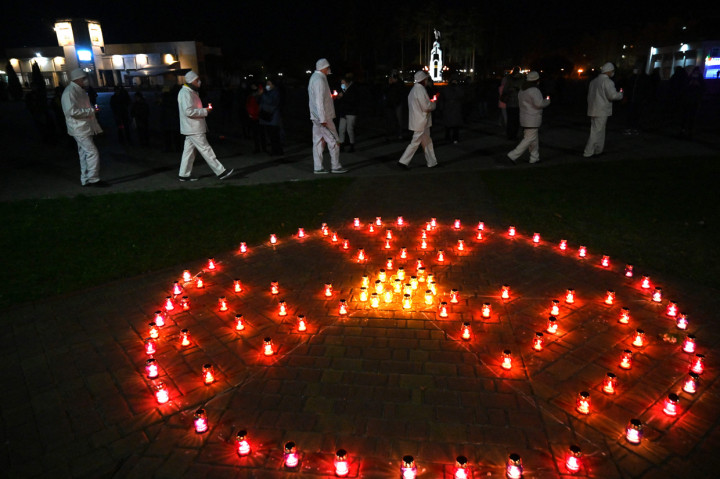 Karyawan pabrik Chernobyl membawa lilin di dekat tanda radioaktif pada upacara peringatan tragedi Chernobyl di monumen korban Chernobyl di Slavutych, Ukraina, kota tempat tinggal personel pembangkit listrik, sekitar 50 kilometer dari lokasi kecelakaan, Minggu, 25 April 2021. Ukraina memperingati 35 tahun bencana Chernobyl yang merupakan kecelakaan nuklir terburuk di dunia pada 26 April 2021.