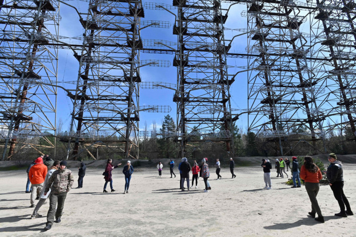 Orang-orang berdiri menyaksikan bagian dari sisa sistem radar Duga-1 yang tidak terpakai yang dibangun Soviet di dekat Chernobyl, Ukraina, Sabtu, 24 April 2021. Peringatan ke-35 dari bencana nuklir terburuk di dunia akan diperingati di negara eks Soviet ini pada 26 April 2021.