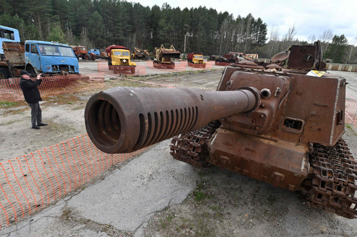 Seorang pengunjung mengabadikan deretan kendaraan alat berat, termasuk kendaraan lapis baja, yang digunakan dalam pekerjaan pemulihan setelah kecelakaan di pembangkit listrik Chernobyl, di kota hantu Pripyat, Ukraina.