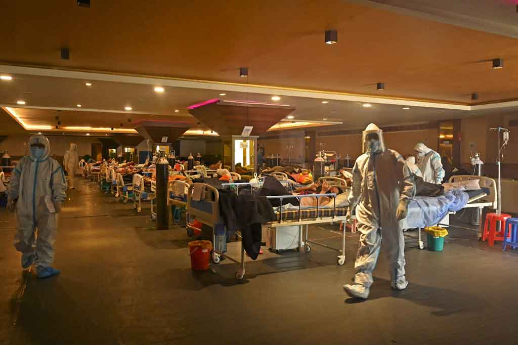 Petugas kesehatan merawat pasien positif covid-19 di dalam ruang perjamuan yang sementara diubah menjadi pusat perawatan covid di New Delhi pada Kamis, 29 April 2021.