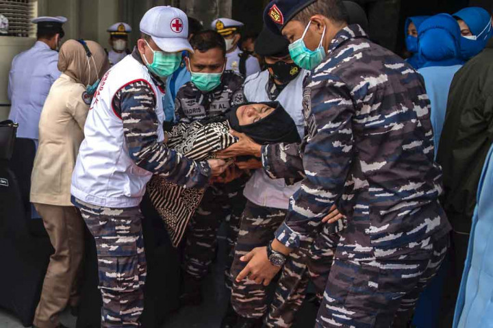 Personel TNI mengangkat keluarga awak KRI Nanggala-402 yang pingsan saat upacara tabur bunga di geladak kapal rumah sakit KRI Dr.Soeharso di lepas pantai Bali.