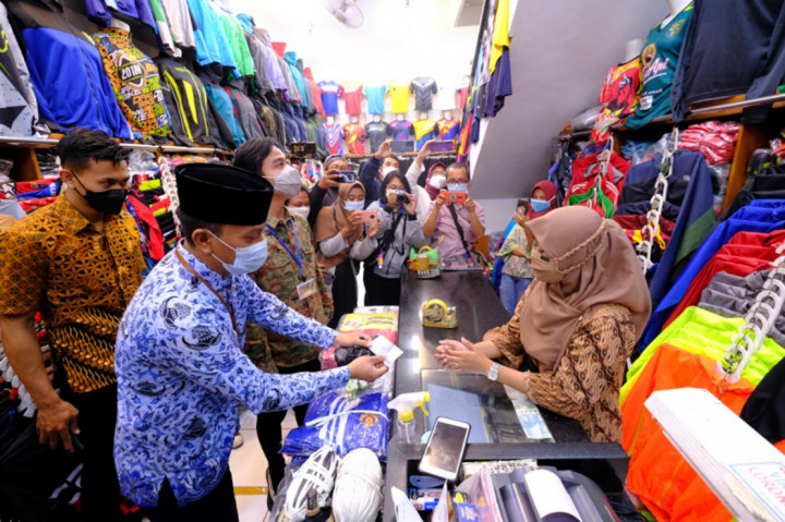 Wali Kota Solo, Gibran Rakabuming Raka bersama Camat Pasar Kliwon berkeliling kawasan pertokoan di Coyudan untuk mengembalikan uang pungli bermodus zakat dan sedekah bersama petugas linmas. 